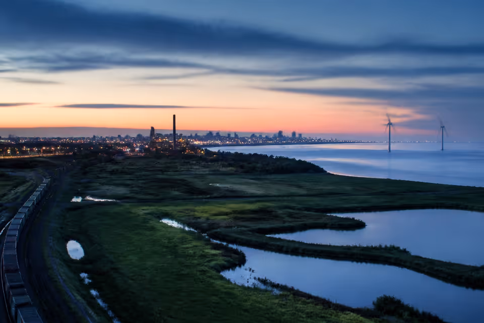 Rail and energy infrastructure meeting wetlands at dawn