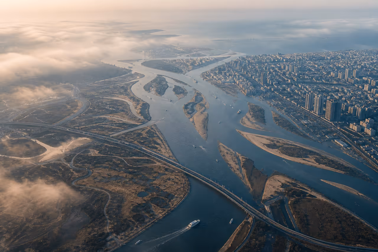 A river delta and road network branching and reconnecting beside a coastal city